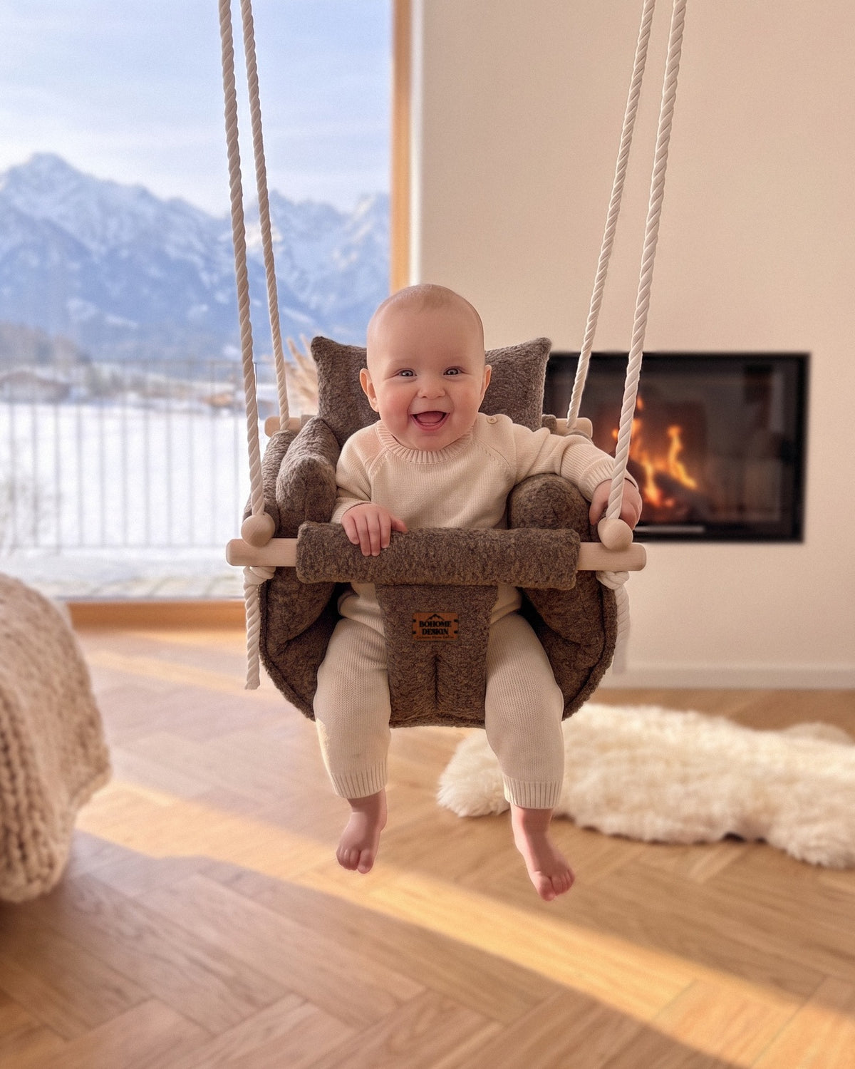BOHOME Premium Babyschaukel Alpine Chalet – fröhliches Baby in der handgefertigten Schaukel im Wohnzimmer mit Alpenblick