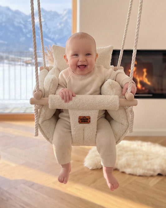 BOHOME Premium Babyschaukel Alpine Dream – fröhliches Baby in der handgefertigten Schaukel im Wohnzimmer mit Alpenblick