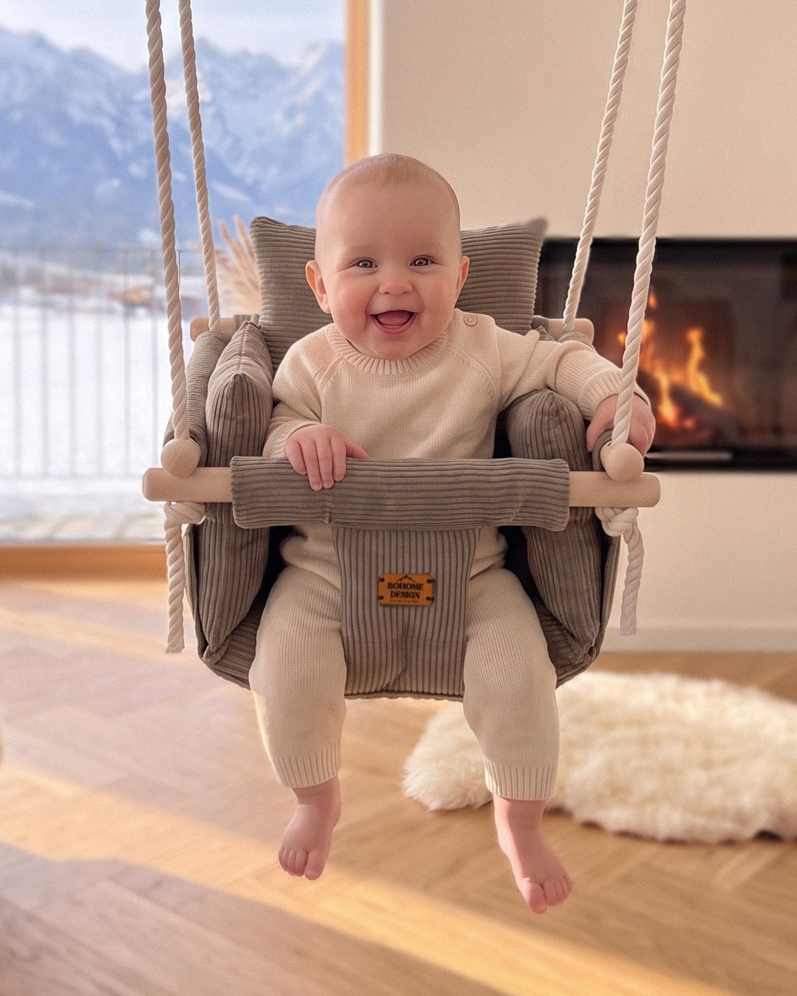 BOHOME Premium Babyschaukel Nougat – fröhliches Baby in der handgefertigten Schaukel im Wohnzimmer mit Alpenblick