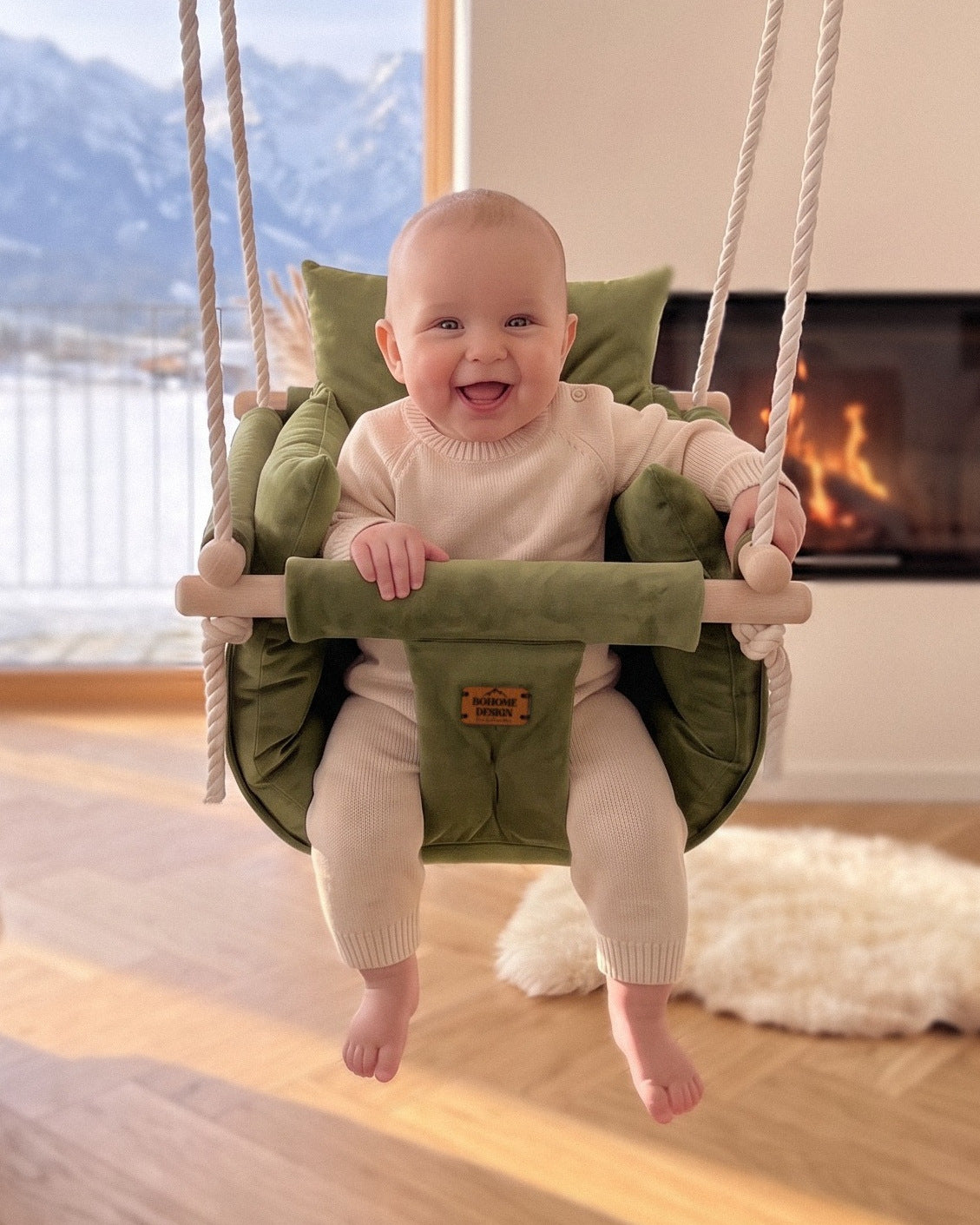 BOHOME Premium Babyschaukel Olive Green – fröhliches Baby in der handgefertigten Schaukel im Wohnzimmer mit Alpenblick